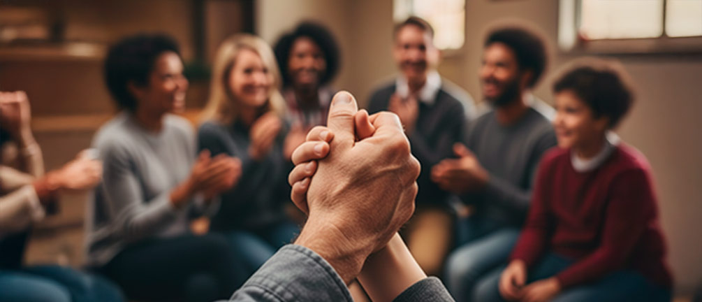 A biblical life lessons. A close-up, warm, and comforting image of three hands (representing different ages or backgrounds) interlinked or braided together, forming a strong bond. The background could be softly blurred, showing a group of diverse people in a warm, supportive church or community setting. Emphasize warmth, strength, and connection. Soft, inviting light.